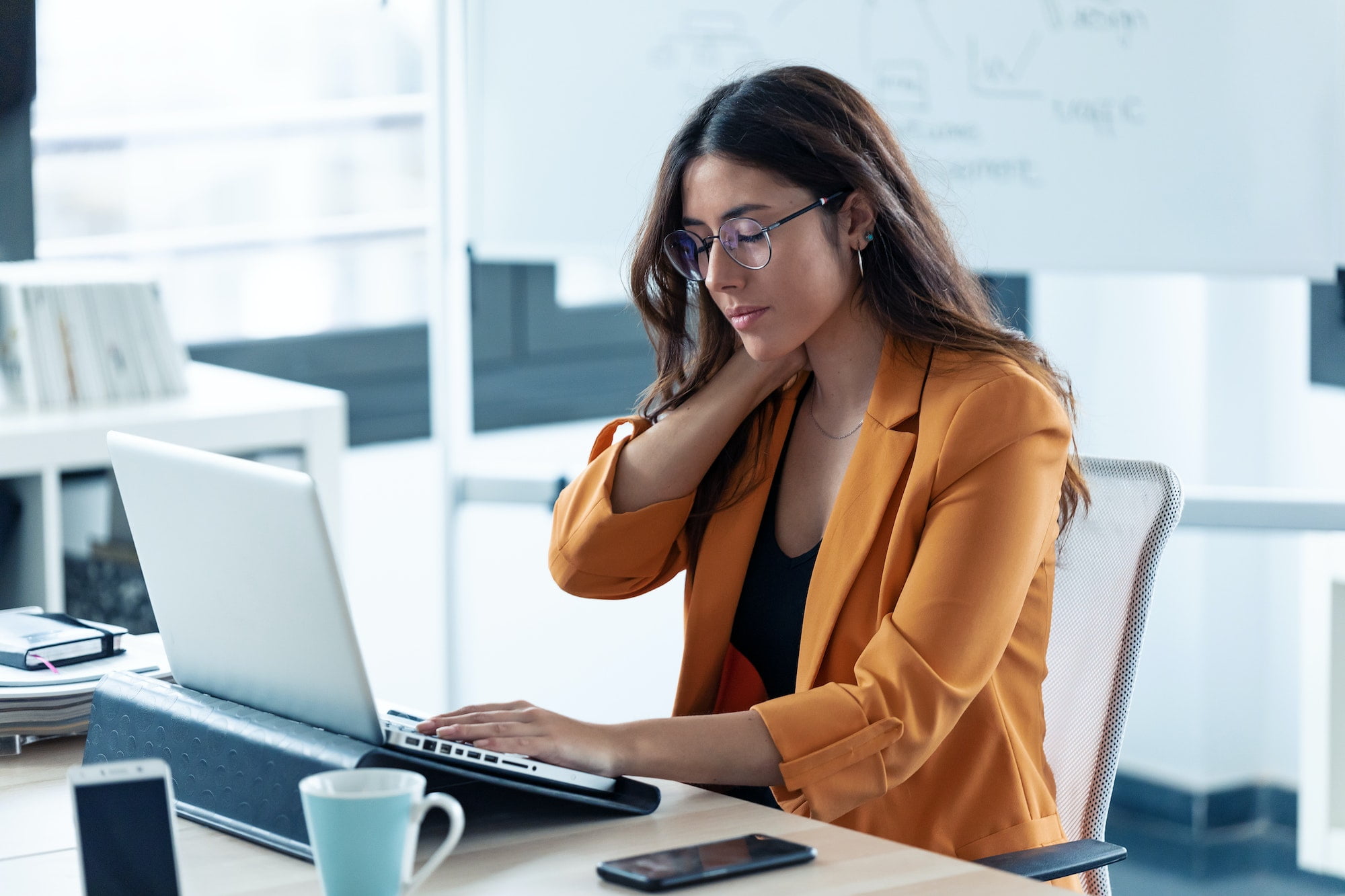 Business young woman with neck pain working with laptop in the office.