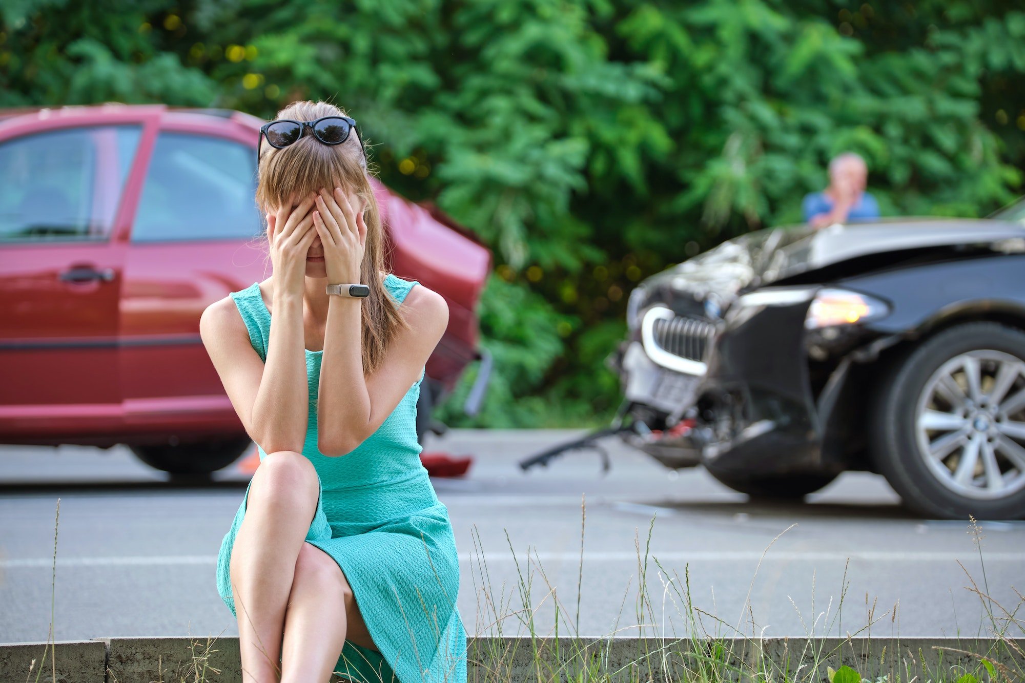 Stressed woman driver sitting on street side shocked after car accident. Road safety and insurance