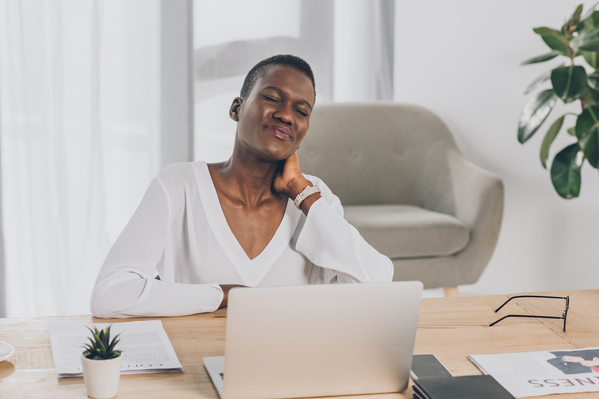 exhausted stylish african american businesswoman touching painful neck in office