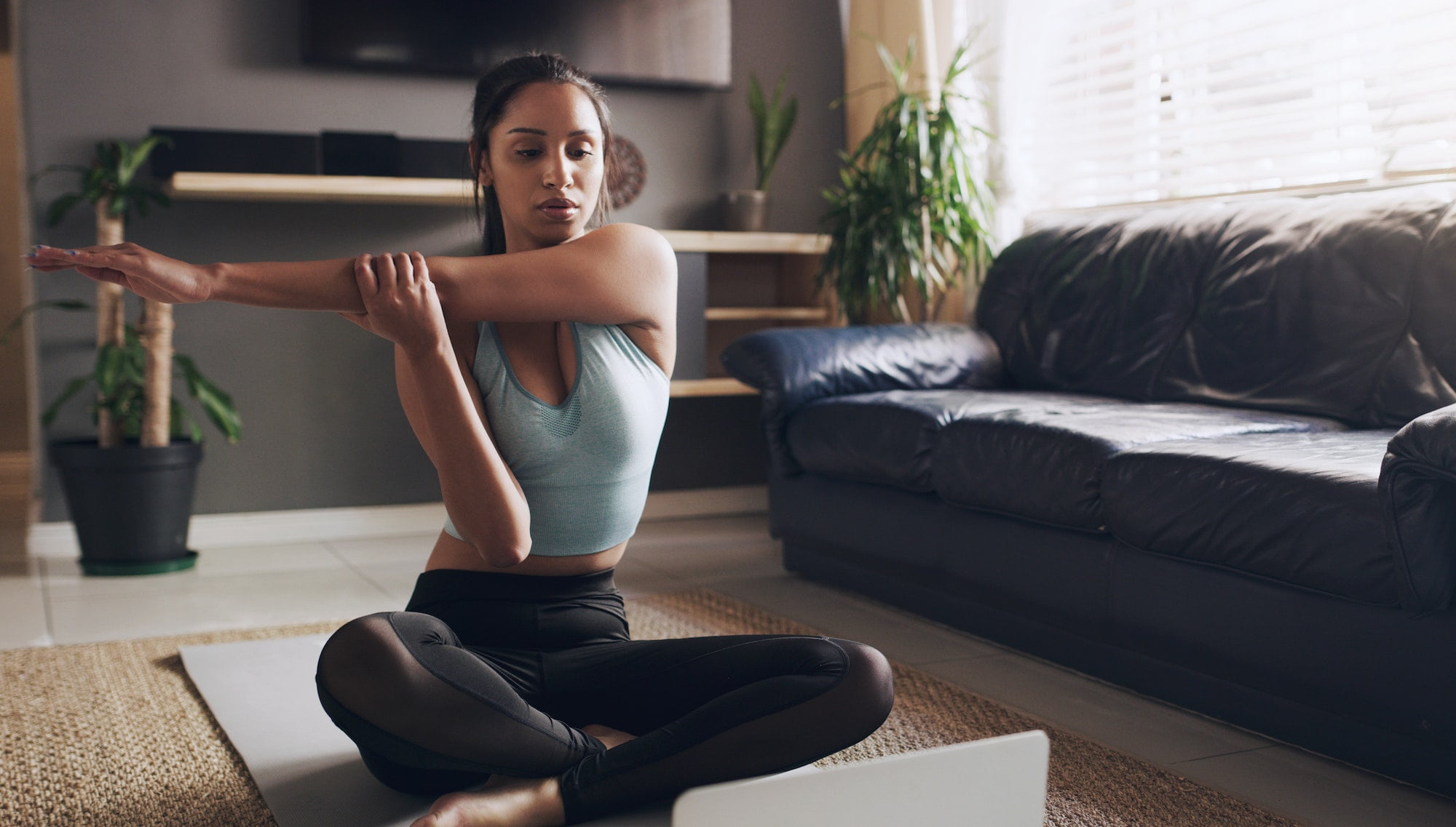 Stretch to prevent injuries. Shot of a young woman stretching before a workout at home.