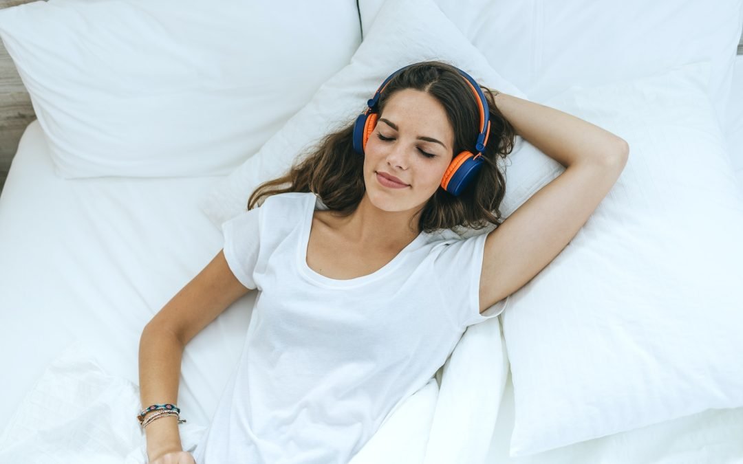 Young woman sleeping in bed at home with headphones