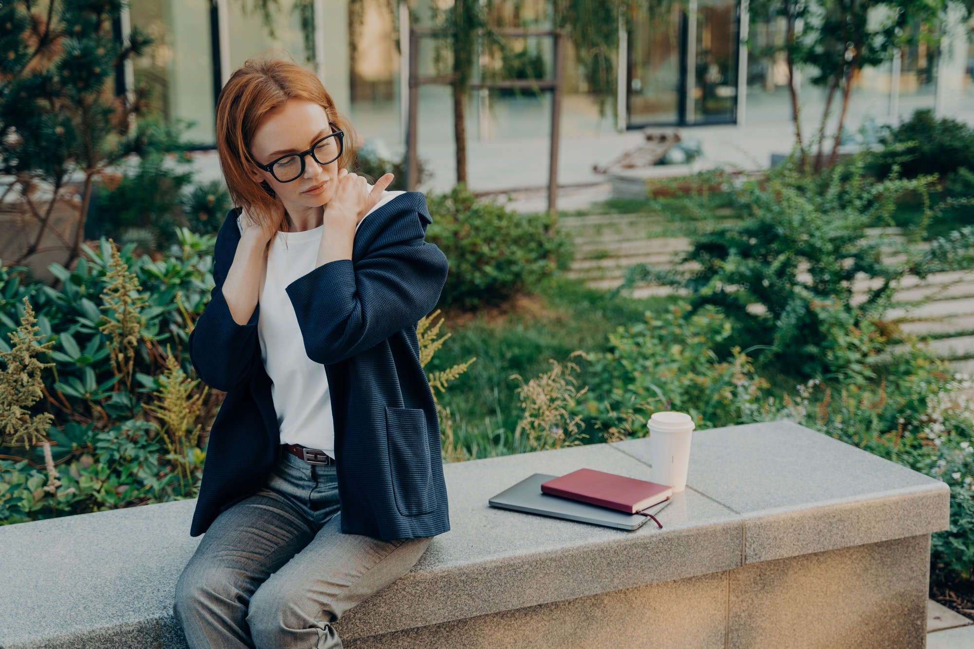 Displeased redhead European woman executive worker suffers from neck pain stiffness in shoulders