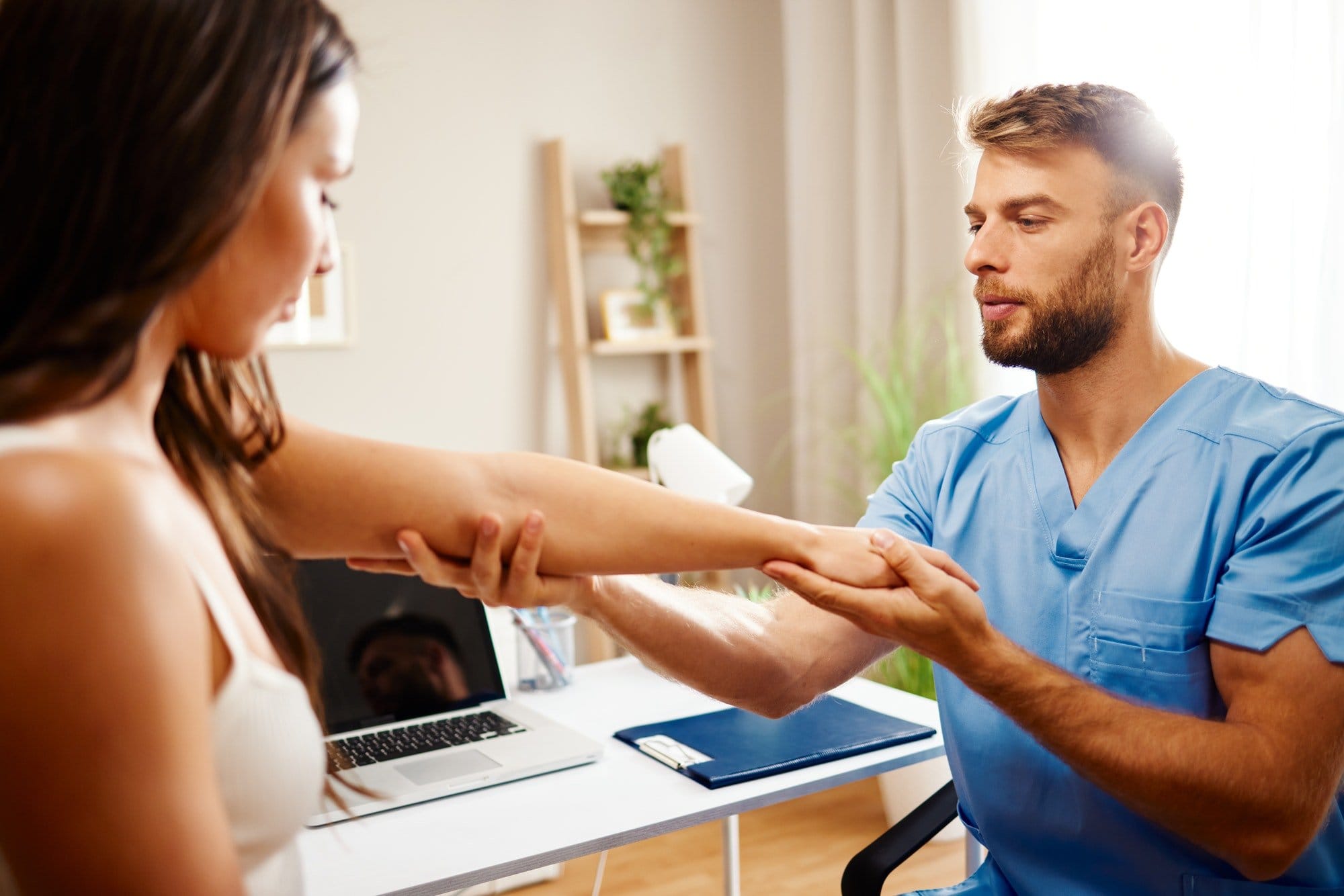 Young woman with elbow pain is being examined by a physiatrist